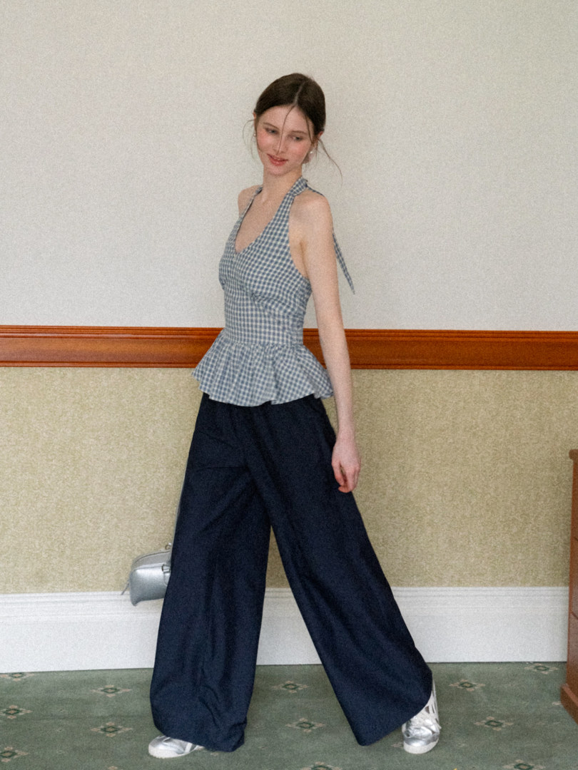 Model wearing a blue gingham halter peplum top with wide-leg navy pants