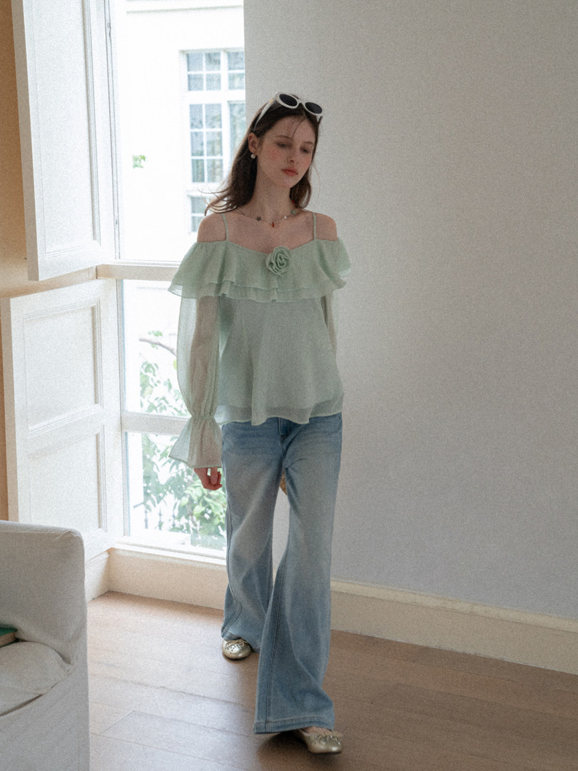 Model wearing a mint off-shoulder ruffled blouse with jeans