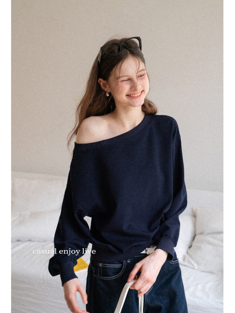 Woman modeling a navy off-shoulder long-sleeve top with dark jeans