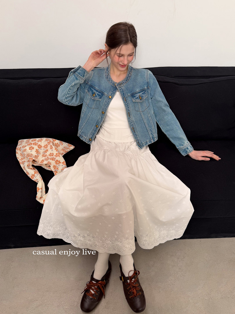 Model wearing a light denim jacket with a white skirt and brown lace-up shoes
