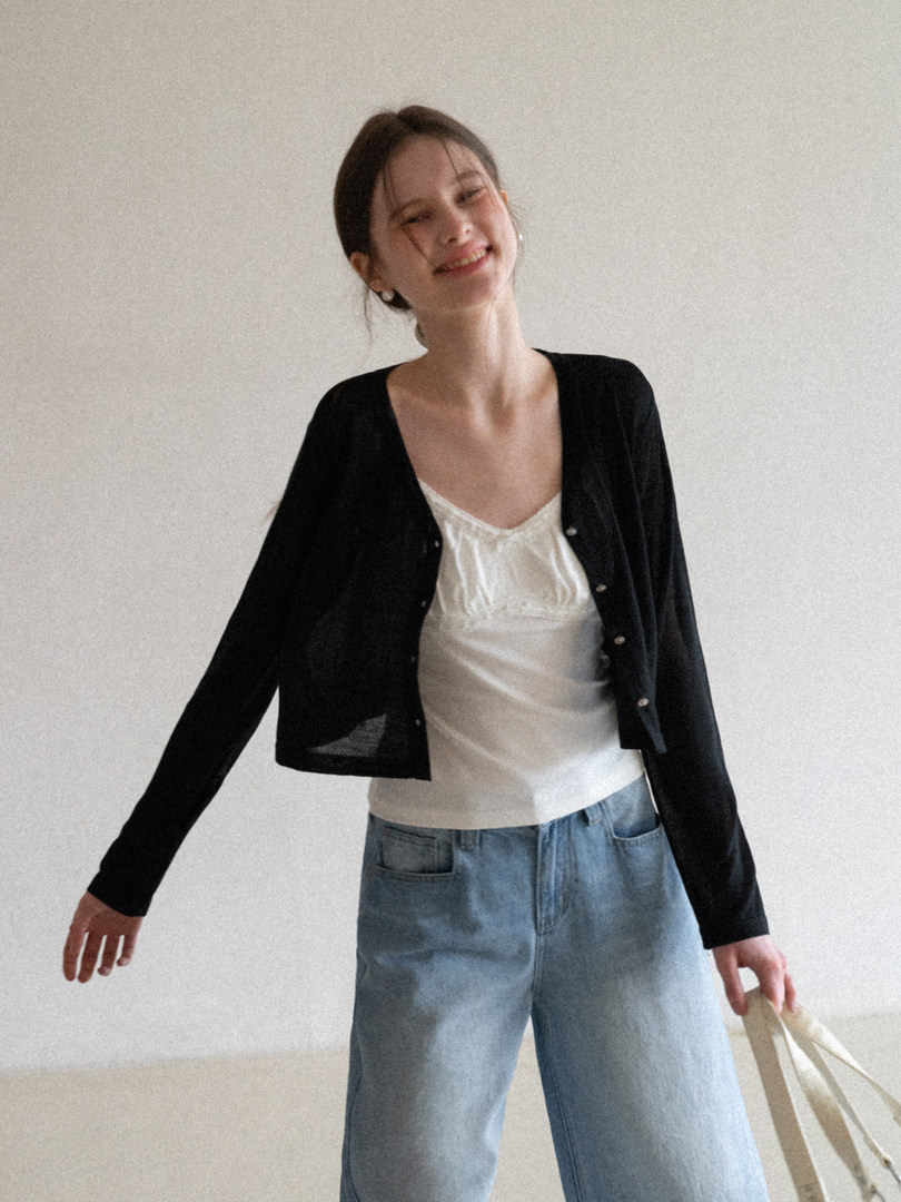 Woman wearing a black cardigan over a white top with light blue jeans