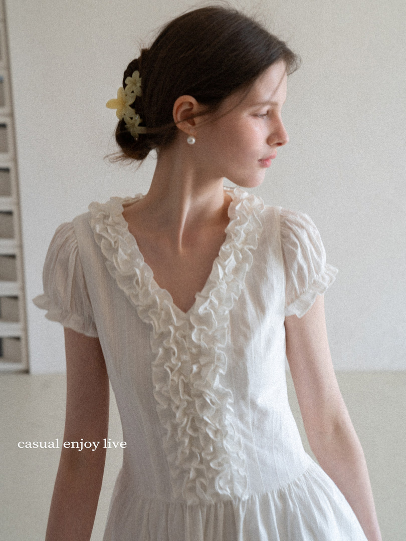 Woman wearing a white ruffled dress with short puff sleeves