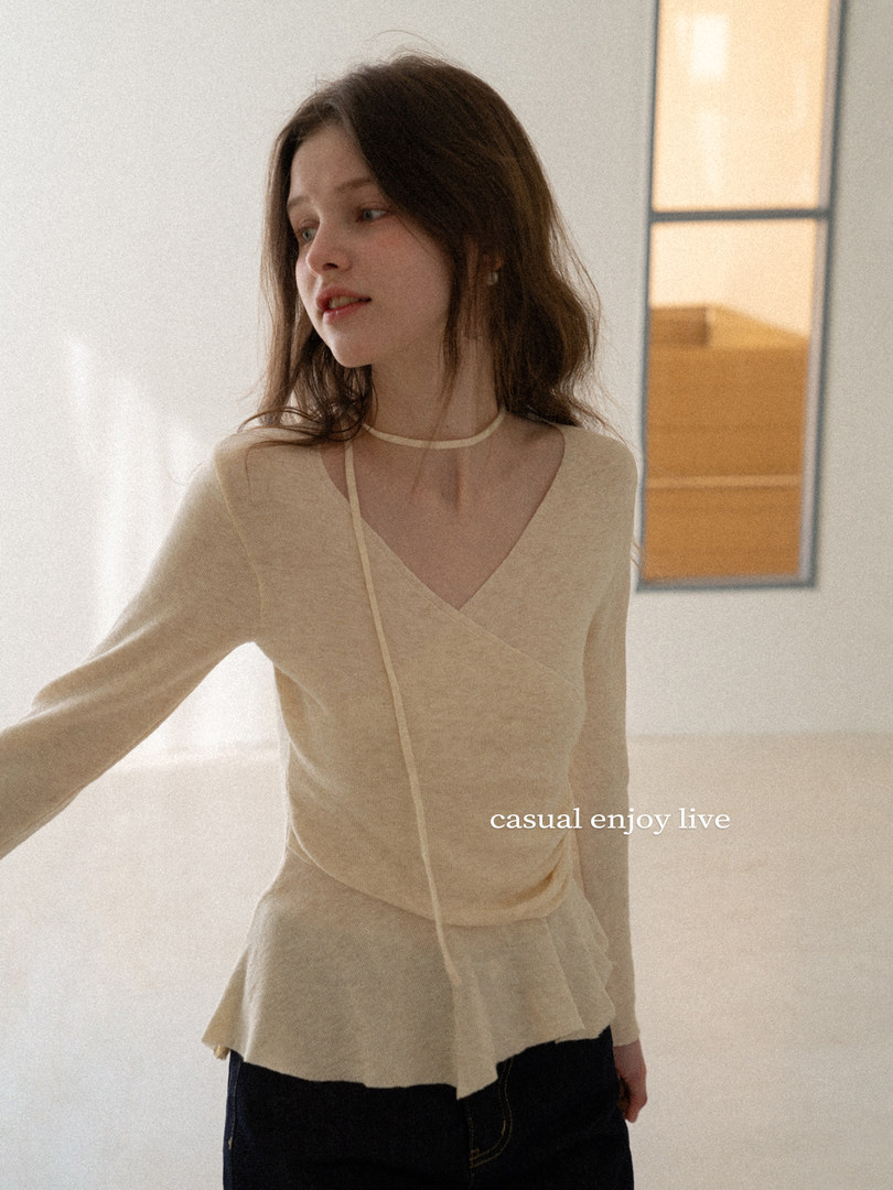 Model wearing a beige long-sleeve wrap-style top
