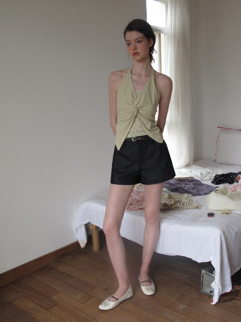 Model wearing a light green halter top, black shorts, and white flats