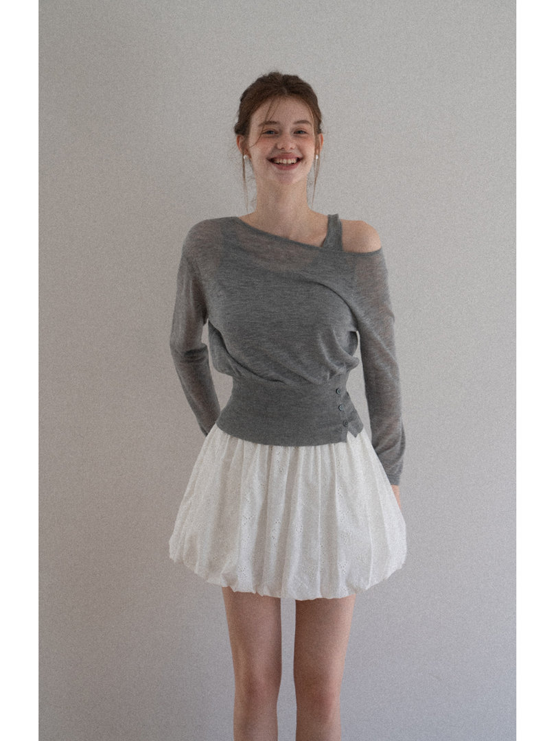 Woman wearing a gray off-shoulder knit top with a white bubble skirt