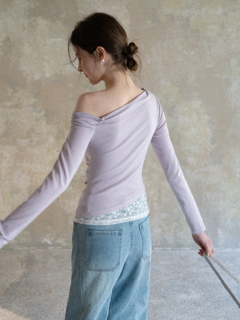Woman wearing a light lavender off-shoulder long sleeve top with jeans