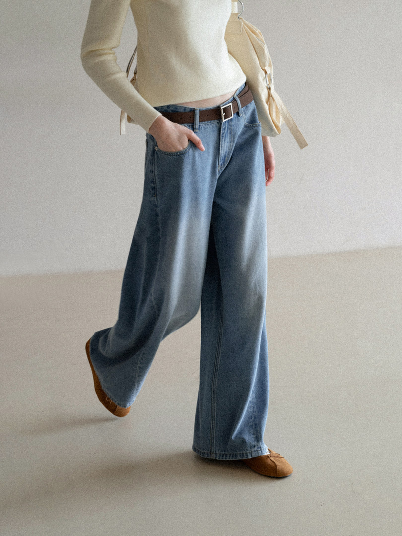 Model wearing wide-leg blue jeans with a cream top and brown shoes