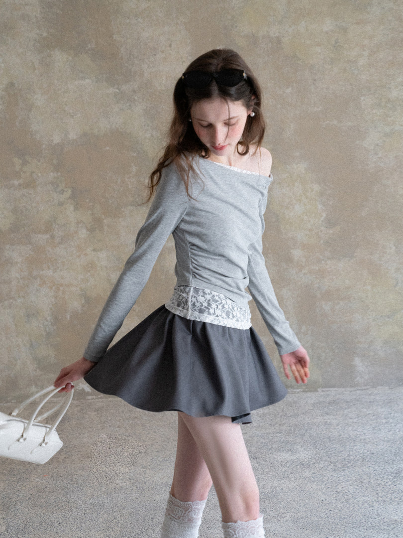 Woman wearing a gray off-shoulder long-sleeve top and skirt with lace detailing