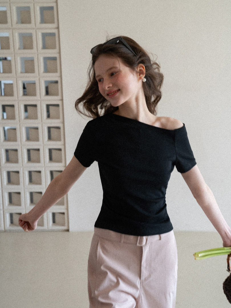 Woman wearing a black off-shoulder short-sleeve top with light pants