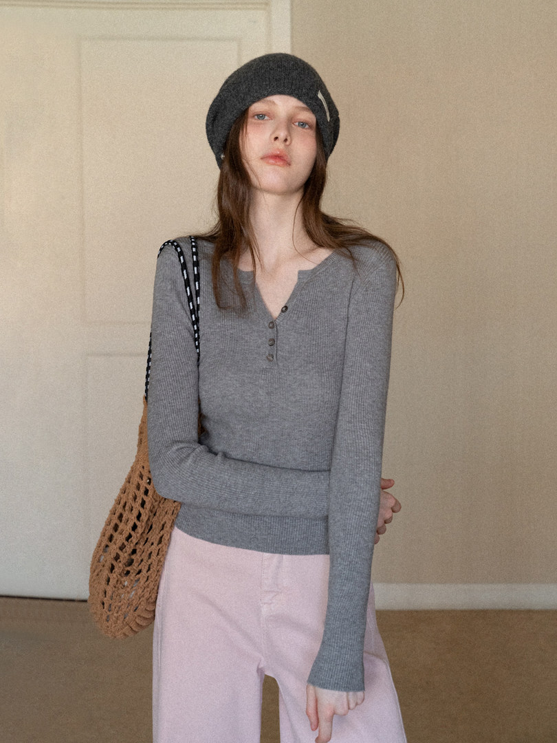 Model wearing a gray ribbed long-sleeve top, black beanie, and pink pants with a woven tote bag