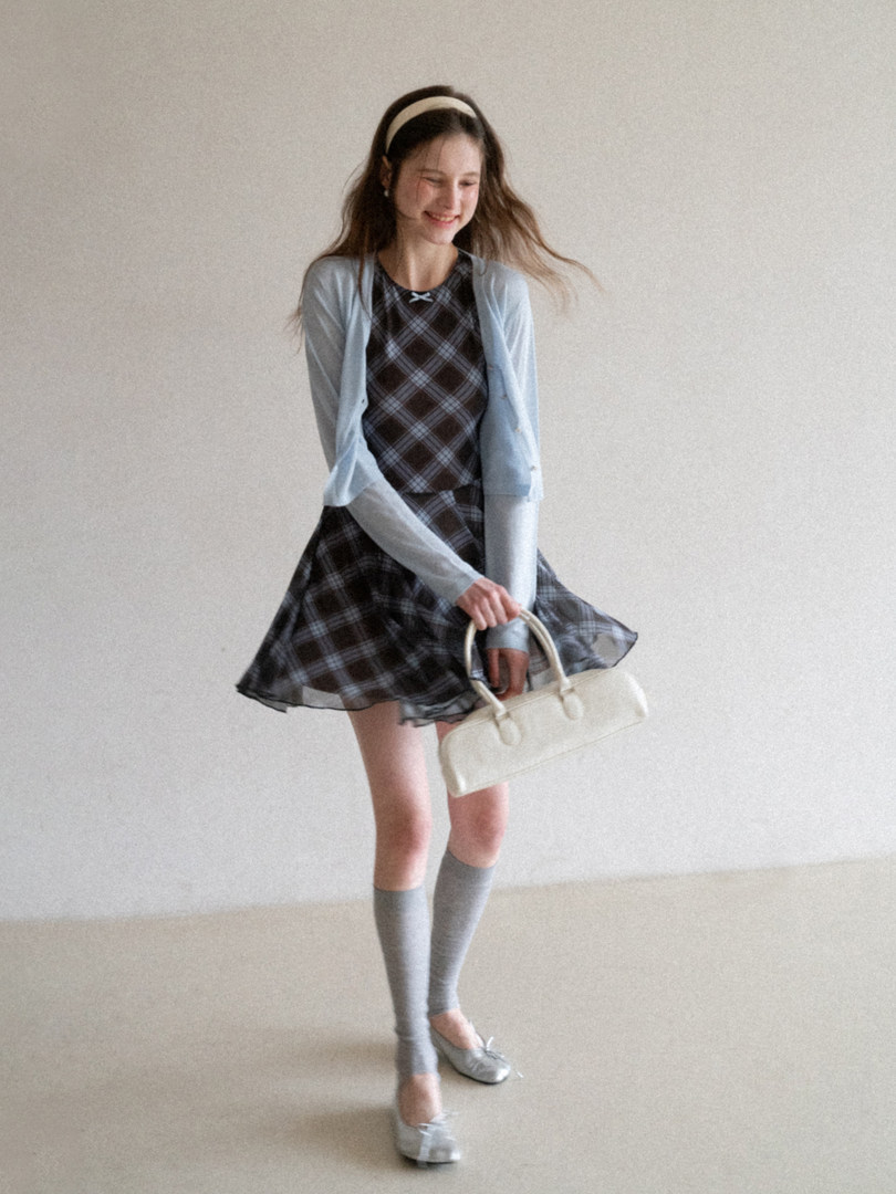 Model wearing a plaid dress with a light cardigan and accessories