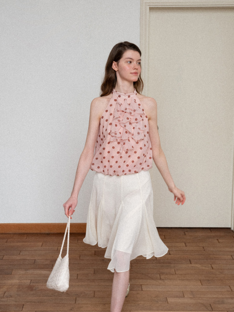 Model wearing a pink polka dot halter top with a white midi skirt