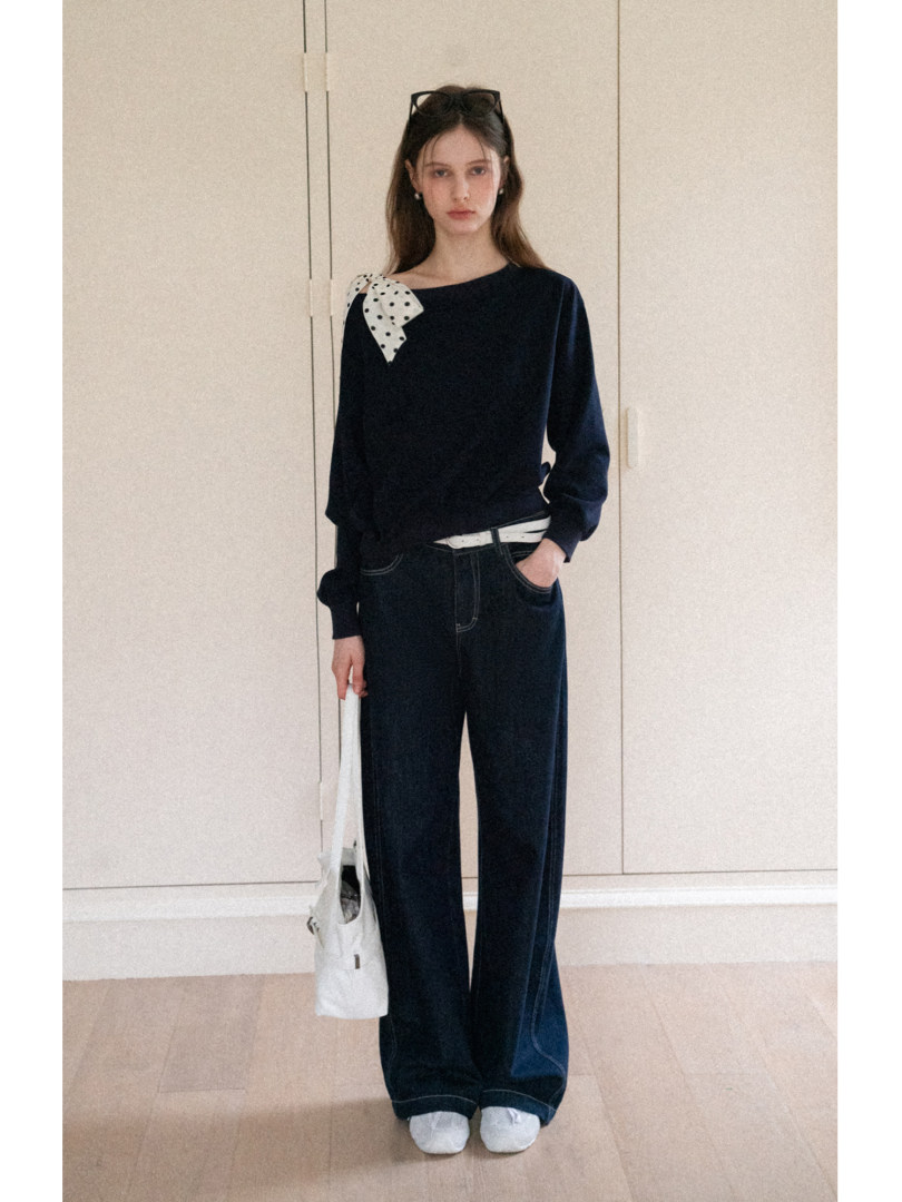 Model wearing a navy long-sleeve top with wide-leg pants and a white tote bag
