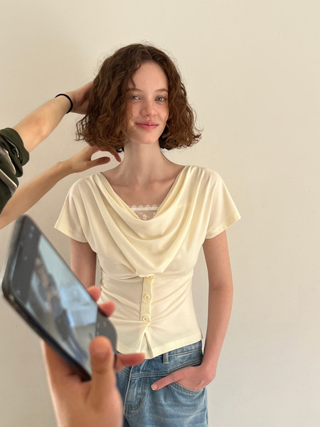Woman wearing a cream draped short-sleeve top with jeans