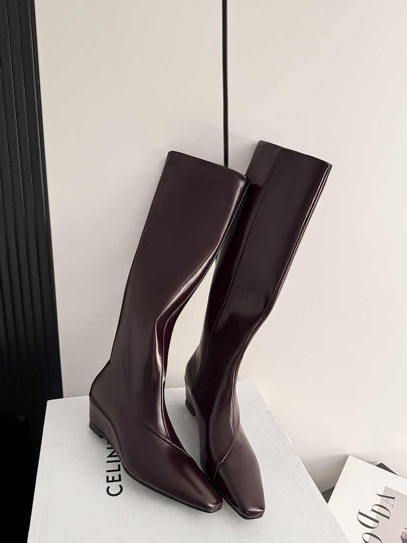 Pair of burgundy knee-high leather boots on a display box