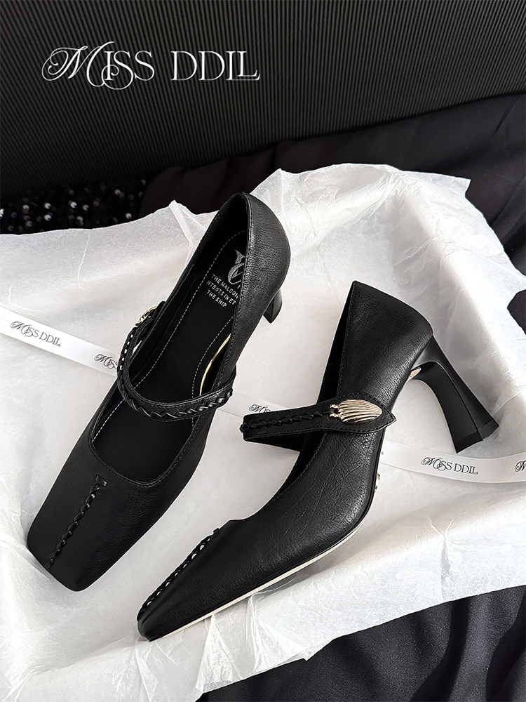 Black heeled pumps with decorative strap detail on tissue paper