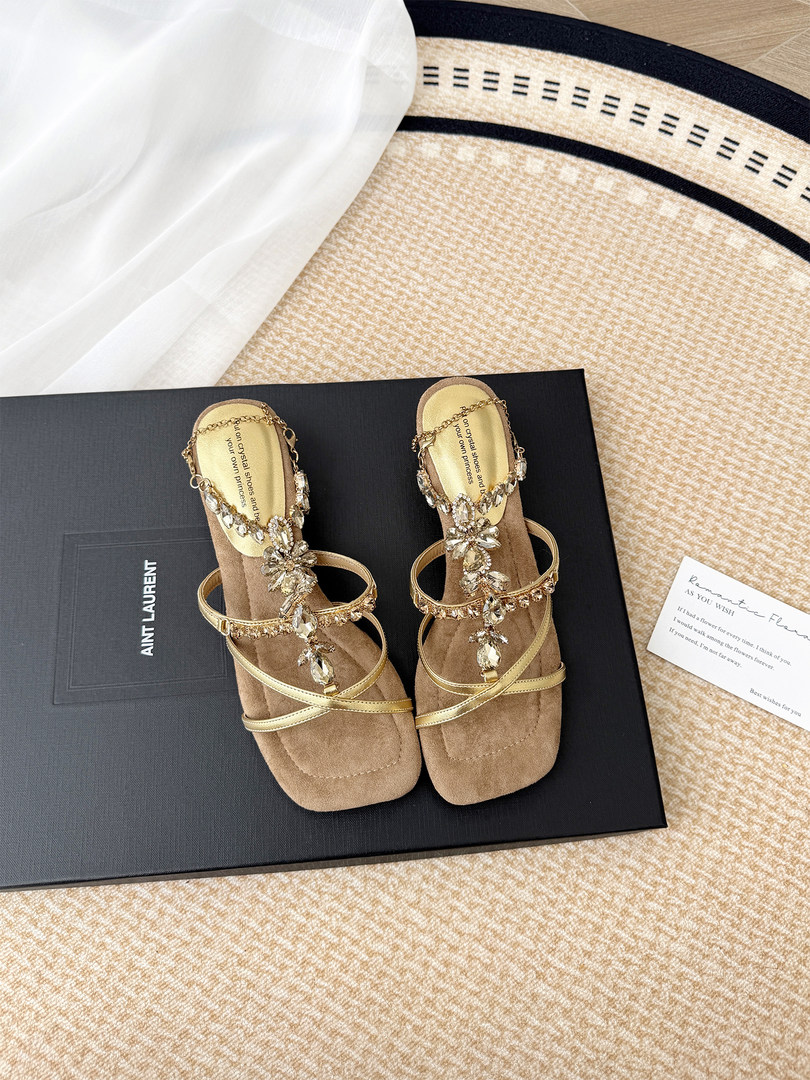 Pair of gold embellished strappy sandals displayed on a shoebox
