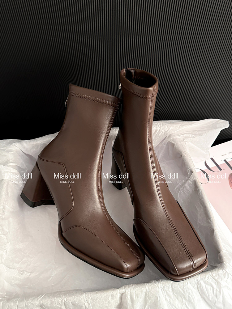 Brown heeled ankle boots on white tissue paper