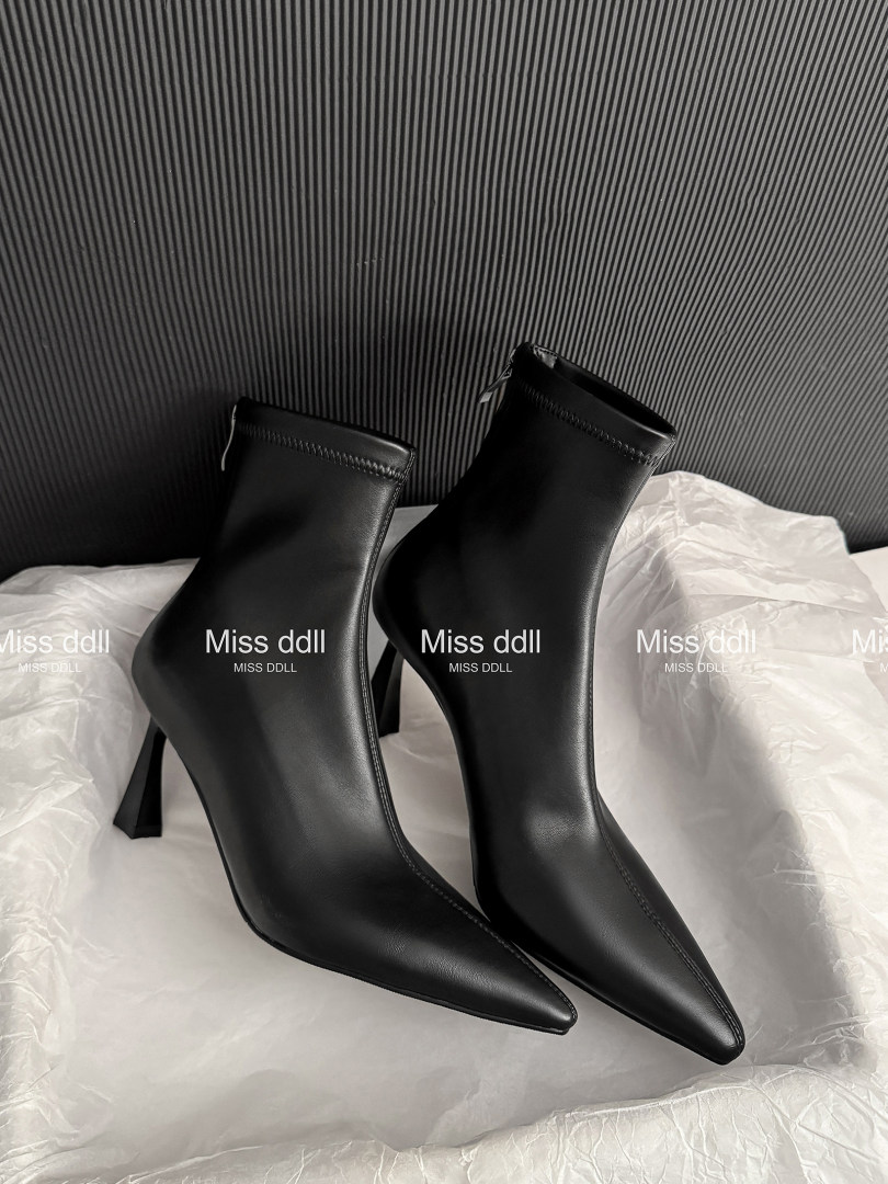 Black pointed-toe high-heeled ankle boots on white tissue paper