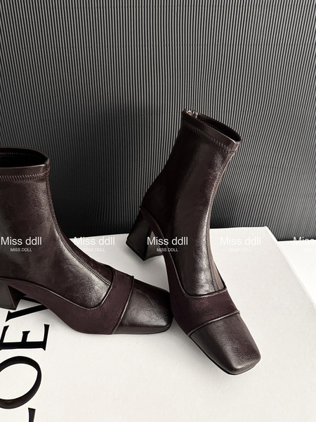 Pair of dark brown ankle boots with block heels on a studio background