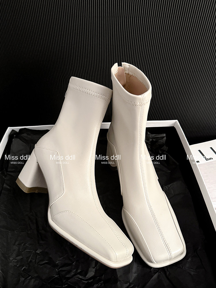 White ankle boots with block heels displayed in a shoe box