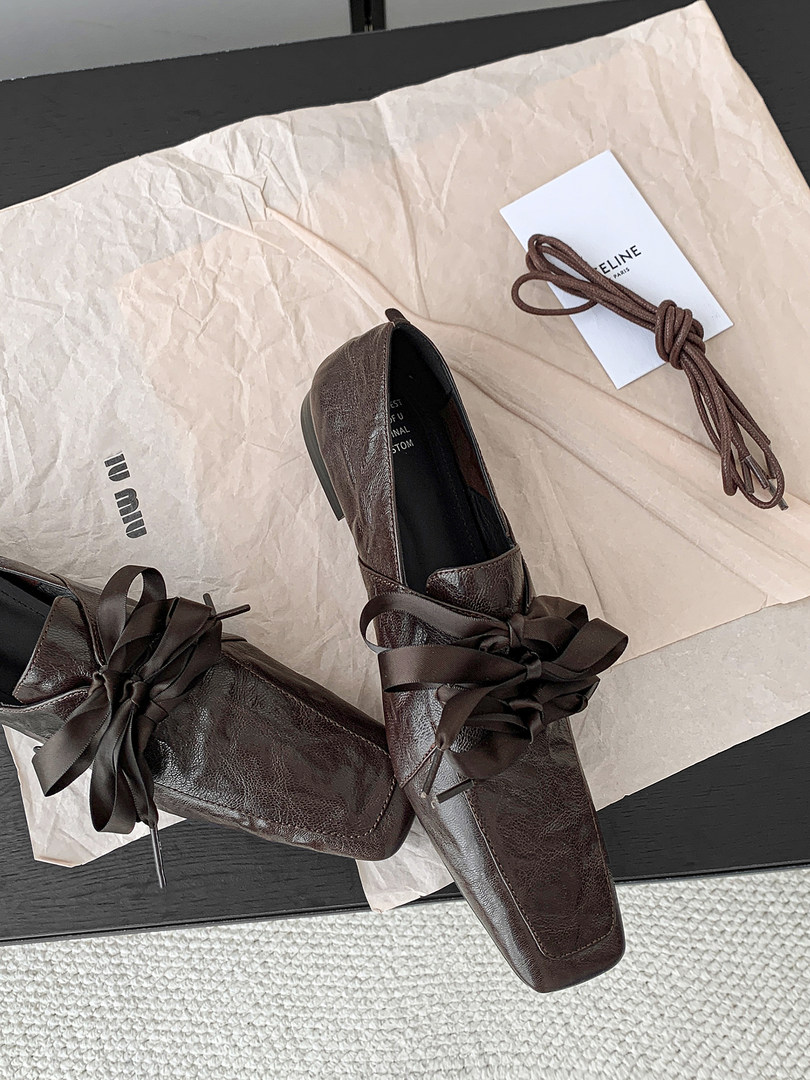 Pair of brown leather lace-up dress shoes with ribbon ties on packaging