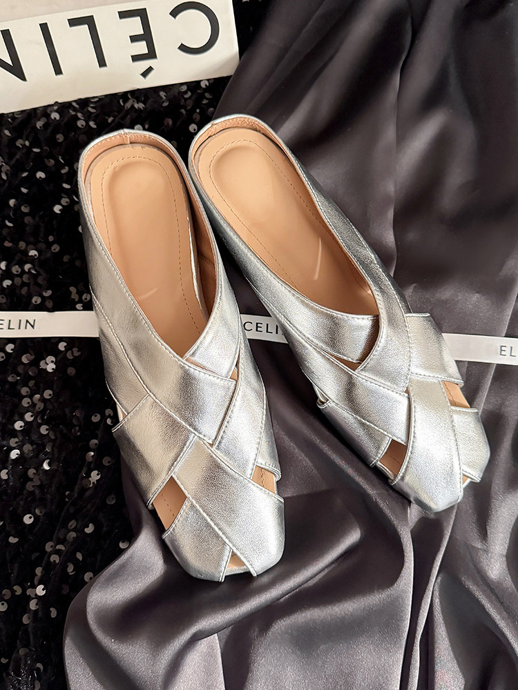 Pair of silver metallic woven slip-on shoes on a satin background