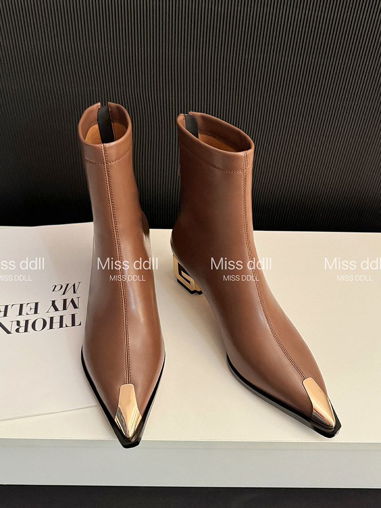 Brown pointed-toe ankle boots with metallic toe caps displayed on a box