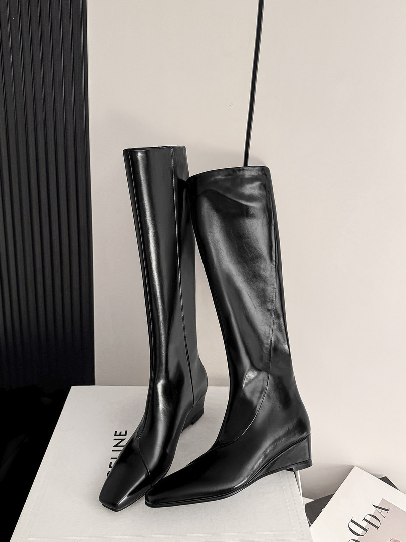 Black knee-high leather boots displayed on a box