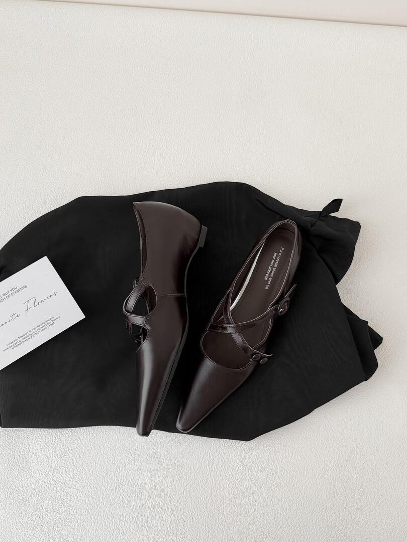 Dark brown pointed-toe slingback heels laid on a black garment