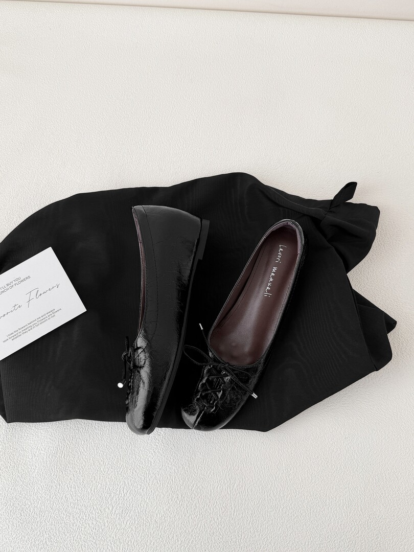 Black patent leather loafers displayed on a black cloth background