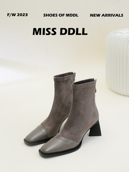 Pair of taupe ankle boots with block heels and contrasting toe caps on a light background