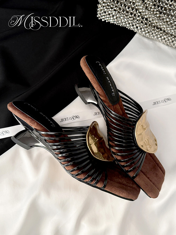 Pair of black strappy heeled sandals with gold accents on display