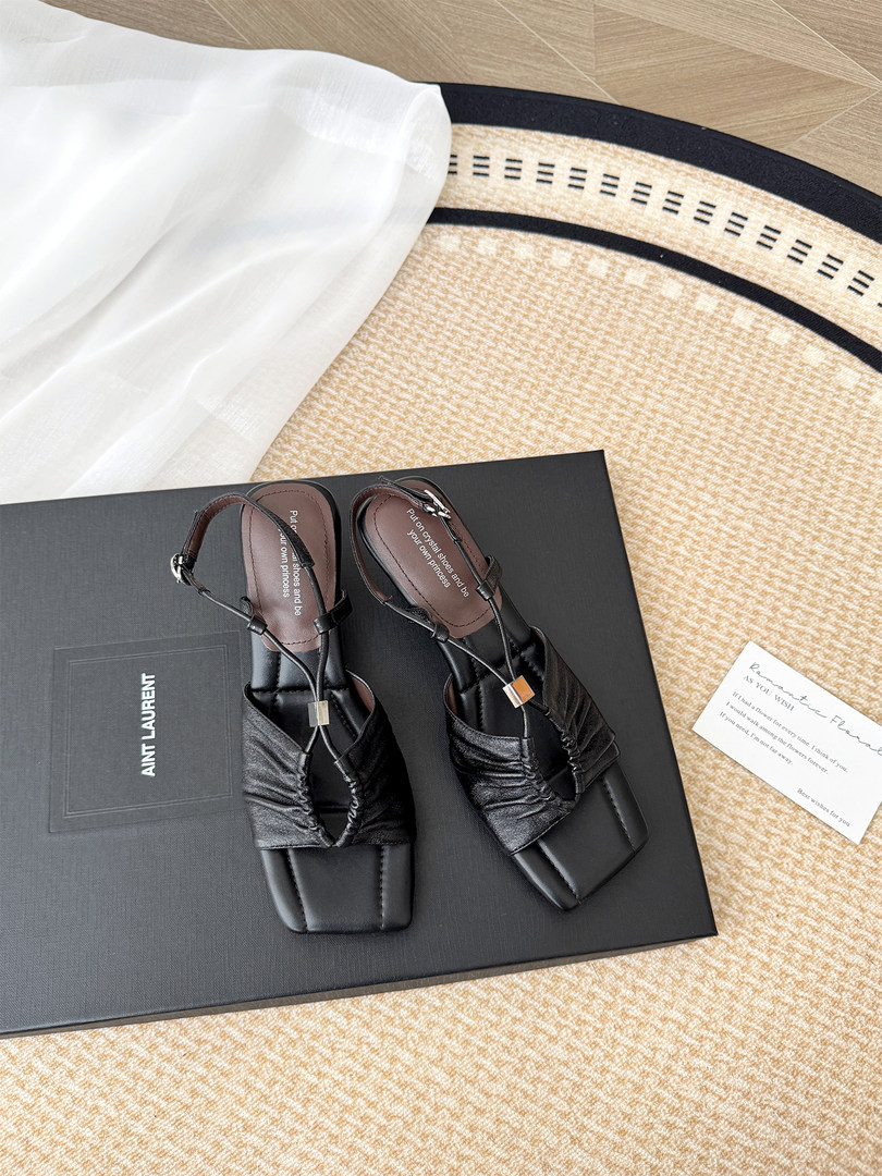 Black strappy heeled sandals displayed on a box