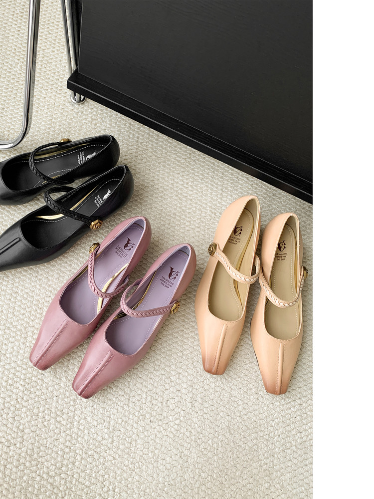 Multiple pairs of pastel and black Mary Jane-style flats laid out on a carpet