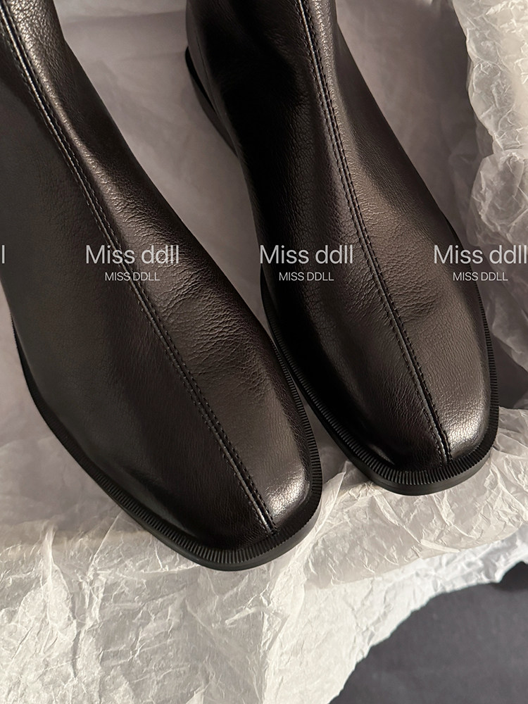 Black leather ankle boots shown close up on tissue paper