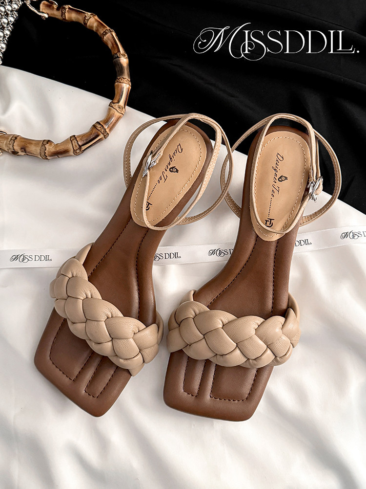 Braided strap beige and brown flat sandals on a fabric background
