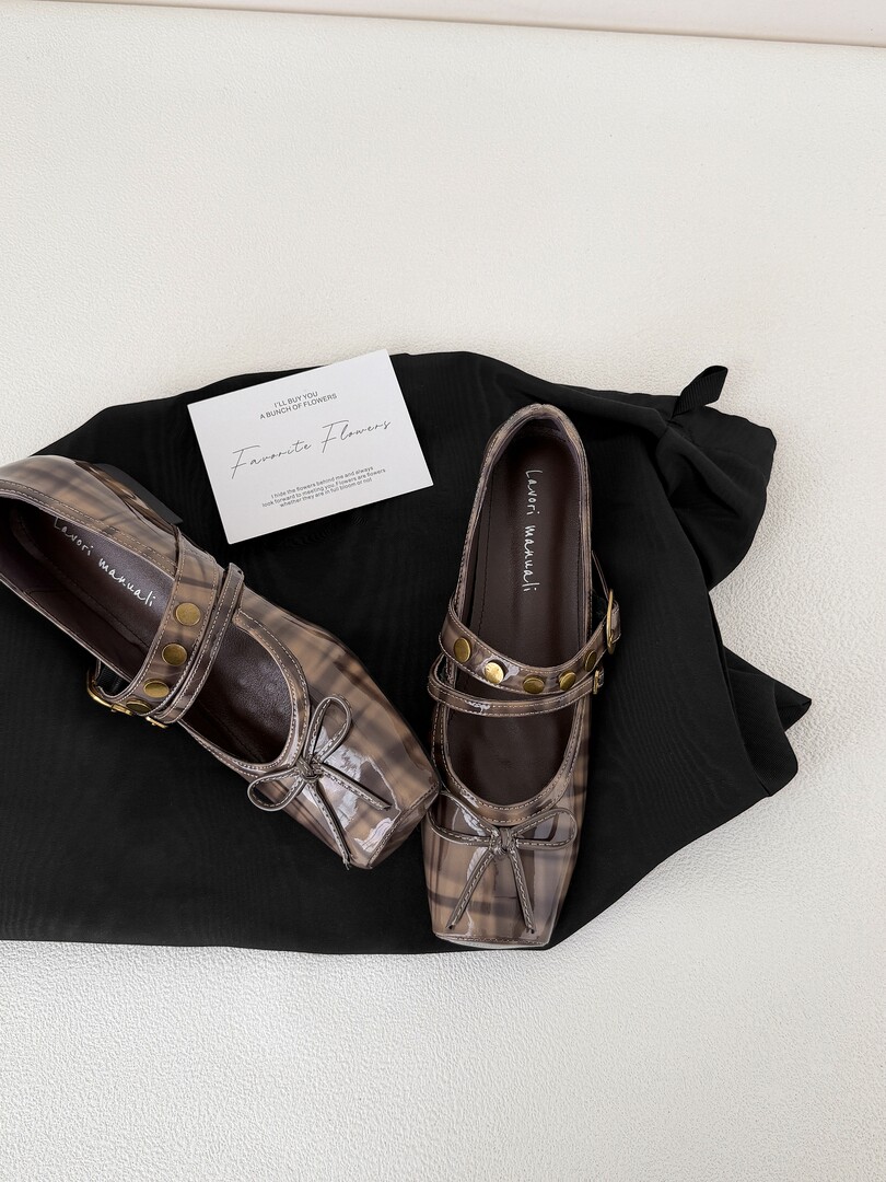 Pair of transparent plaid Mary Jane flats with metal studs laid on black fabric