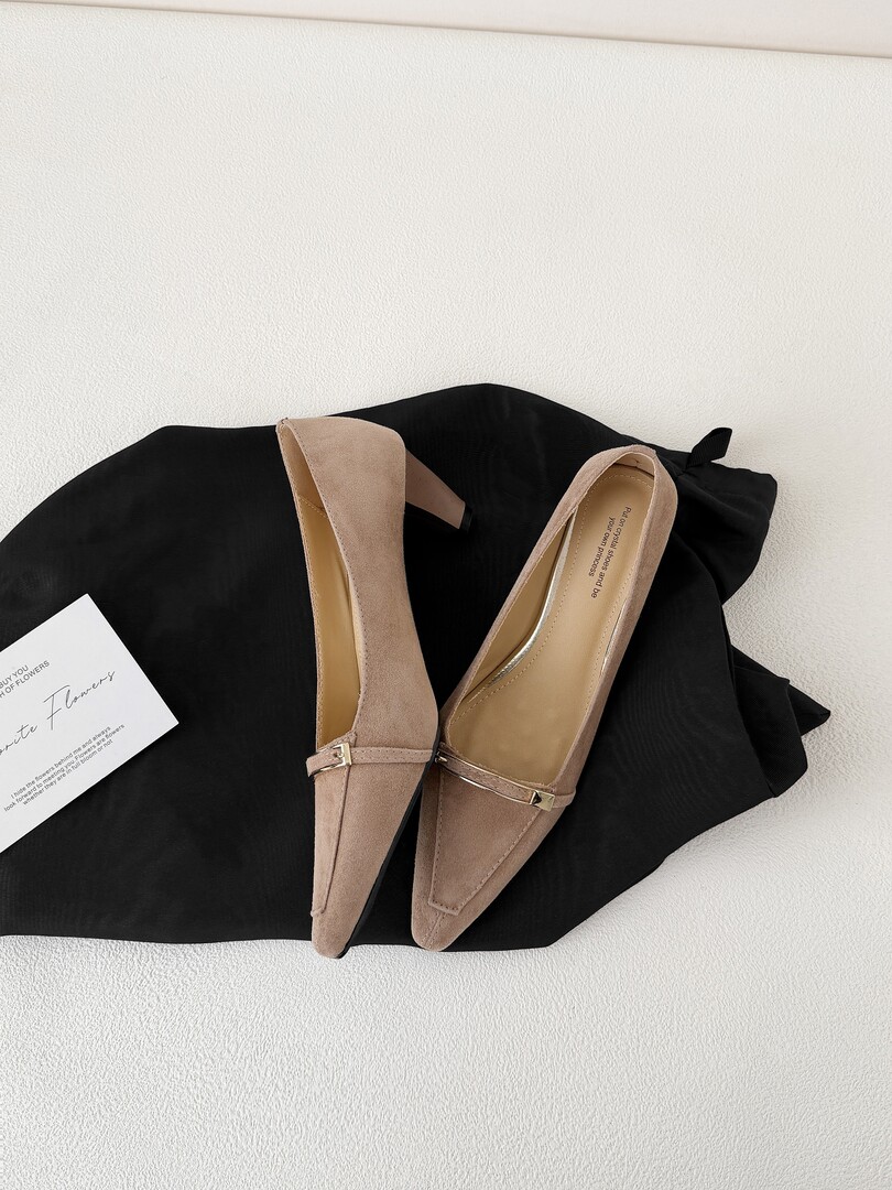 Pair of beige pointed-toe high heels laid on a black fabric background