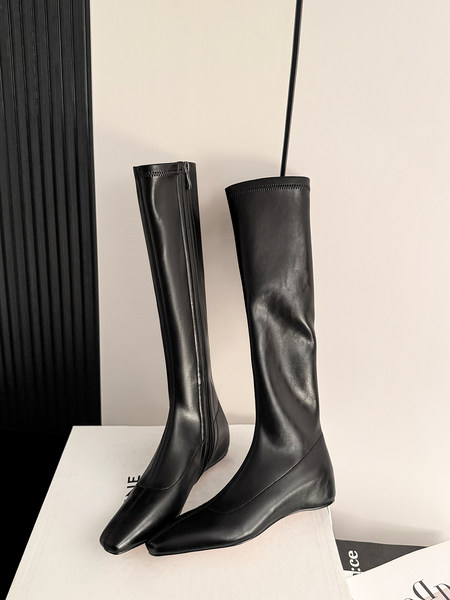 Black knee-high pointed-toe boots displayed on a white surface