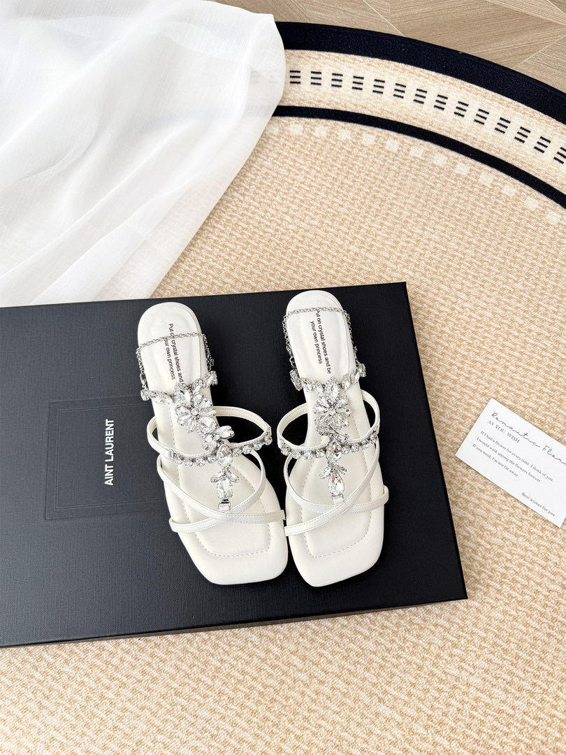 White embellished heeled sandals displayed on a black shoebox