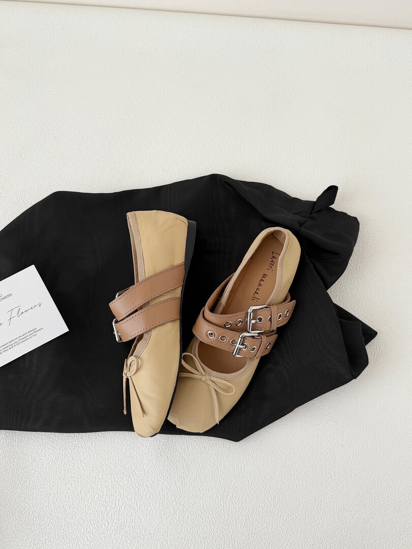 Pair of beige slingback flats with buckle straps on black fabric