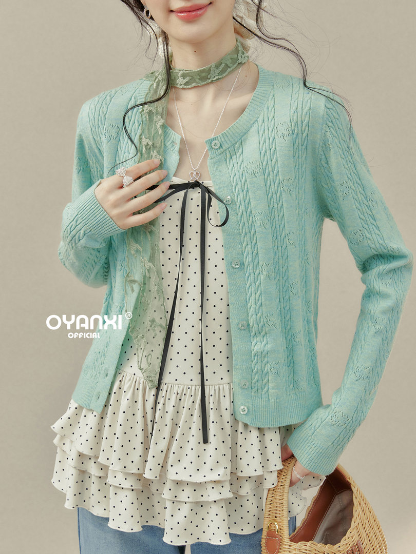Model wearing a mint cable-knit cardigan over a polka dot ruffled dress