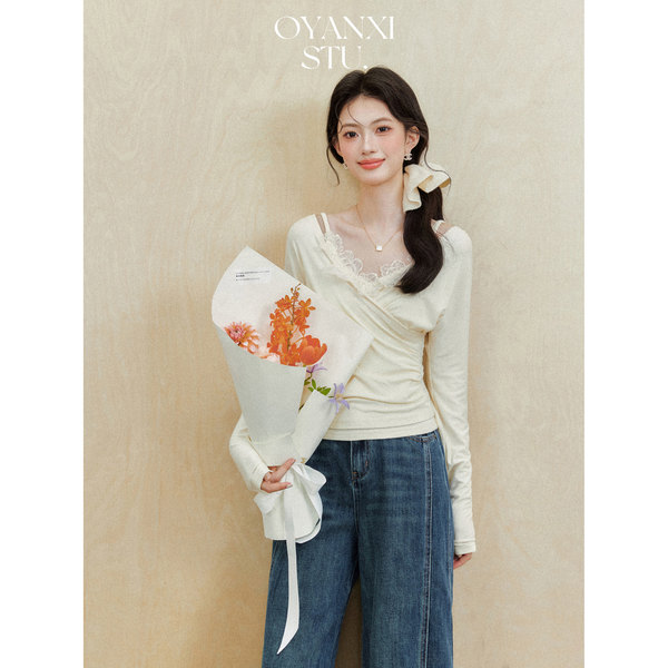 Model wearing a cream lace-trim long-sleeve top with blue jeans while holding a bouquet