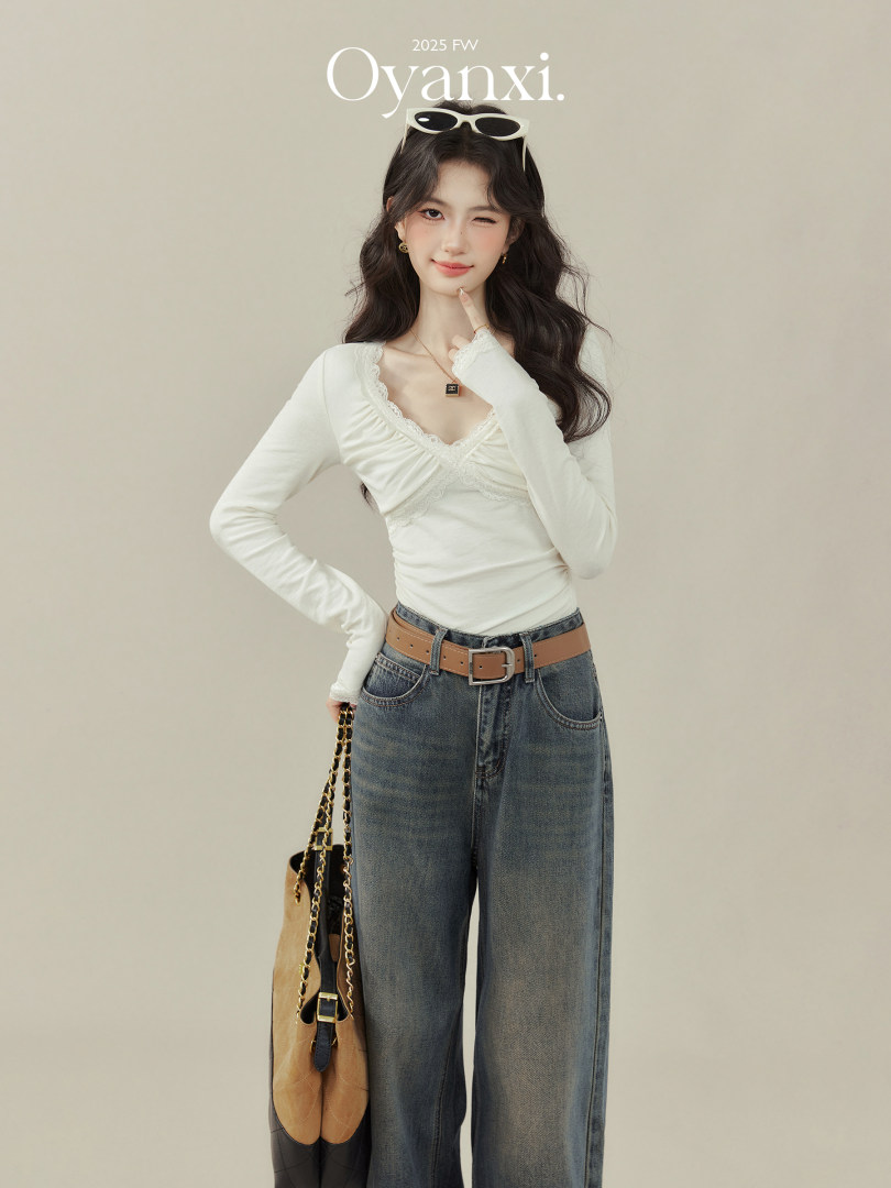 Fashion model wearing a white lace-trim long-sleeve top with wide-leg jeans and a handbag