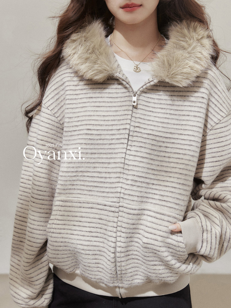 Model wearing a striped zip-up jacket with a faux fur collar