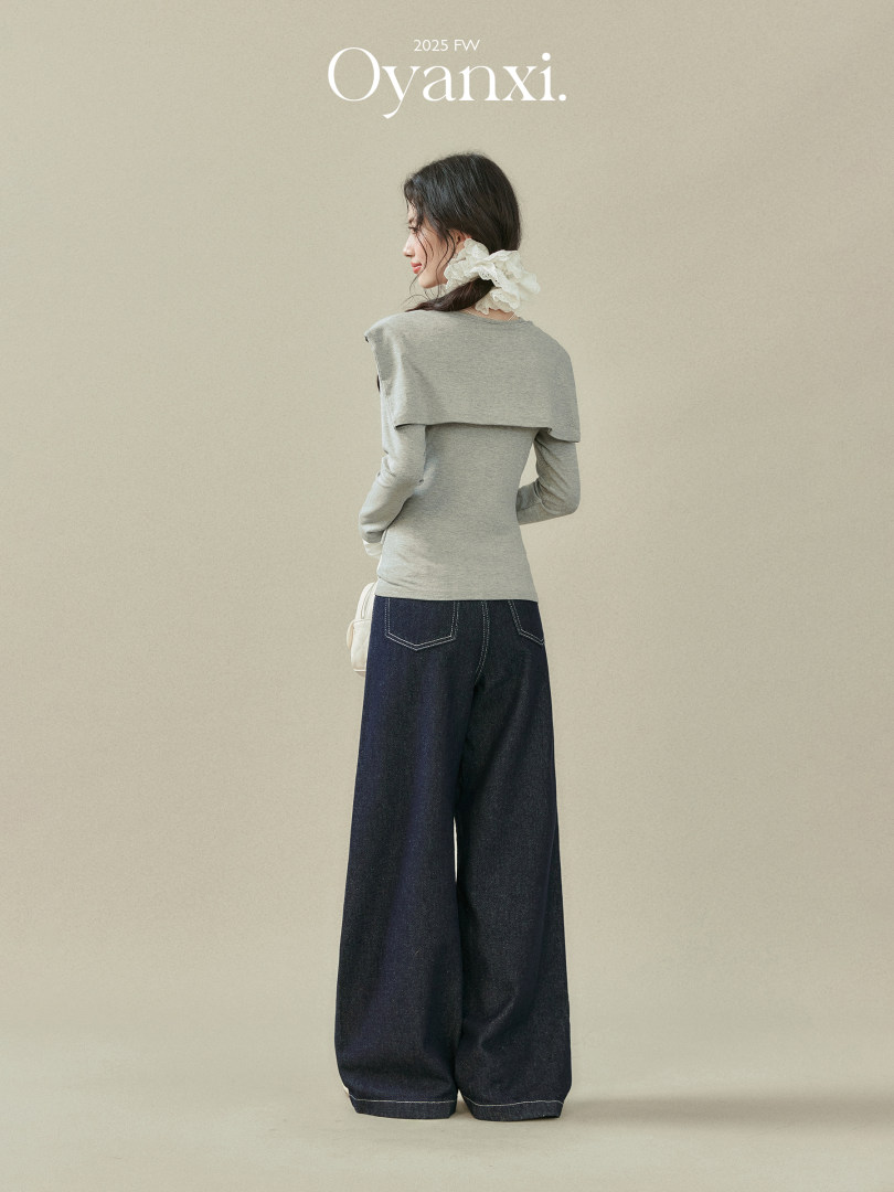 Model wearing a gray long-sleeve top with wide-leg dark jeans
