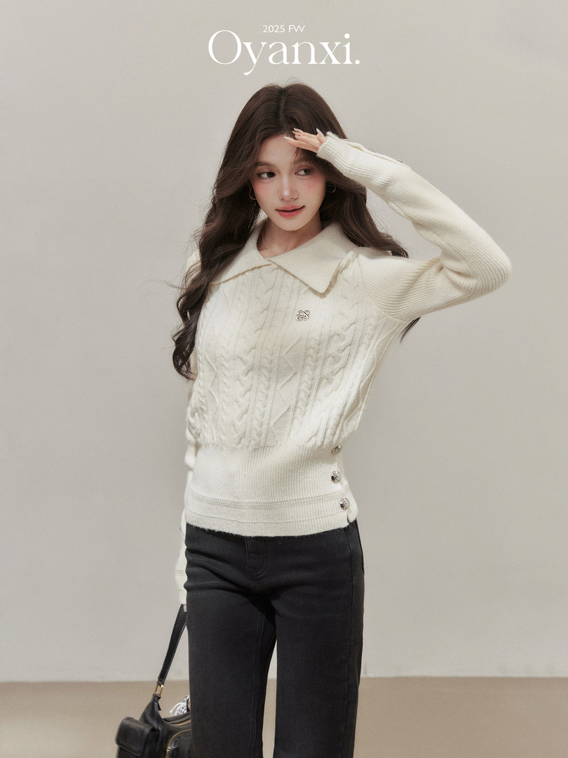 Model wearing a cream cable-knit sweater with dark pants