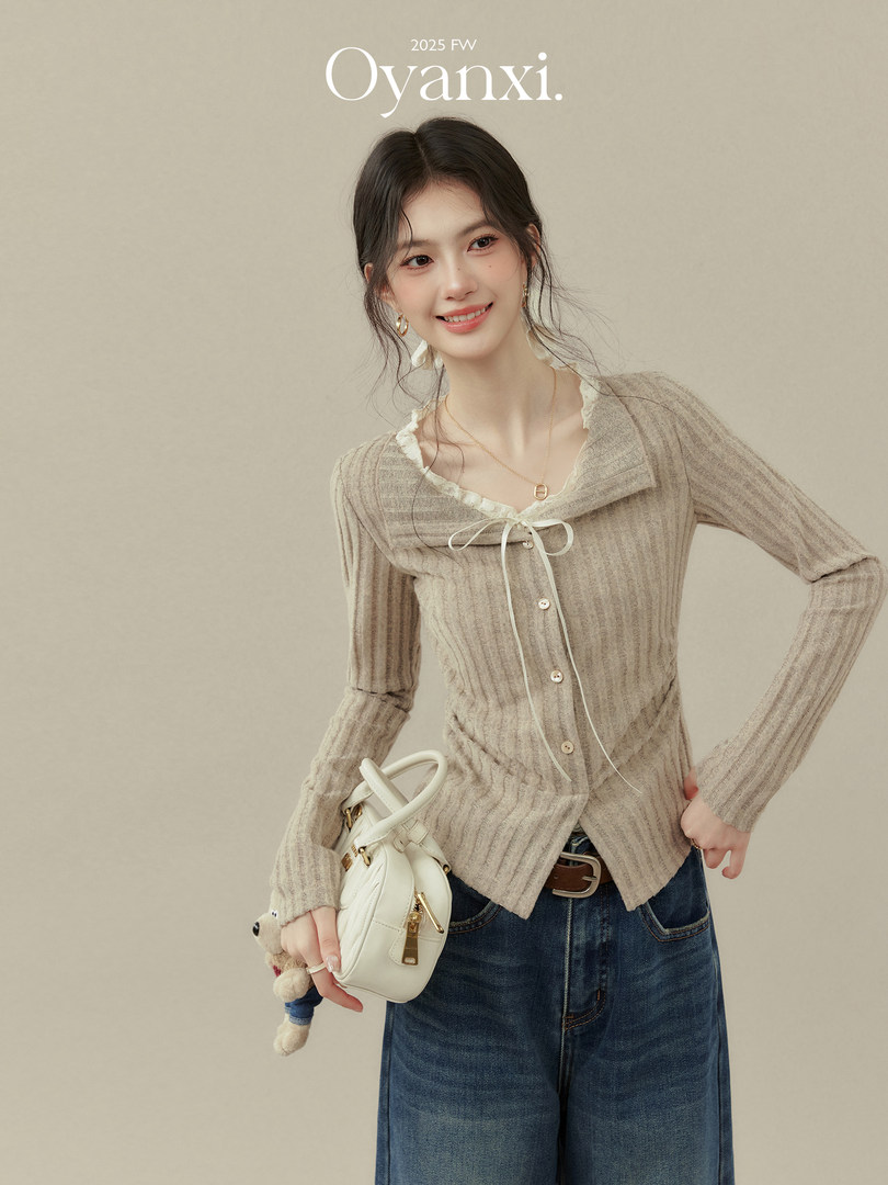 Model wearing a beige ribbed knit cardigan with lace trim and a white handbag