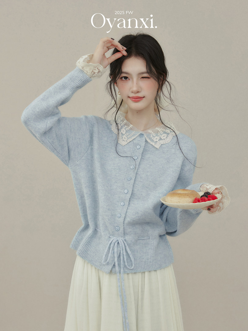 Model wearing a light blue lace-collar knit cardigan with buttons and drawstring hem